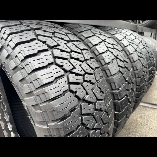 Close-up of three all-terrain tires lined up side by side, tread facing the camera.