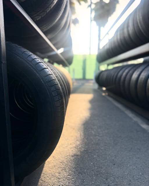 Low-angle view down a row of used tires on outdoor racks in late afternoon light.